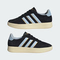 Zapatilla Adidas retro de gamuza negra y celeste sobre mostrador